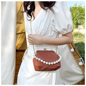 Détail du sac tressé en paille avec poignée en perles et bandoulière en chaîne dorée