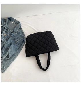 Close-up of black quilted puffer tote bag with soft texture and rhombus stitching detail