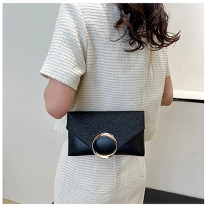 Detail of black envelope clutch with large gold ring buckle and sparkling textured finish