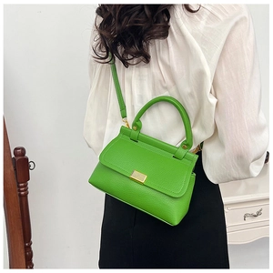 Detail of bright green lychee grain leather crossbody bag with golden metal lock and handle