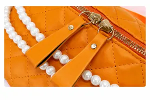Détail du sac orange en cuir PU matelassé avec double fermeture éclair et chaîne en perles