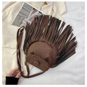 Detail of bohemian brown suede saddle bag featuring long fringe and woven edge details
