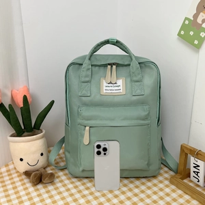 Detail of mint green campus backpack with WAVAL label on a checkered tablecloth