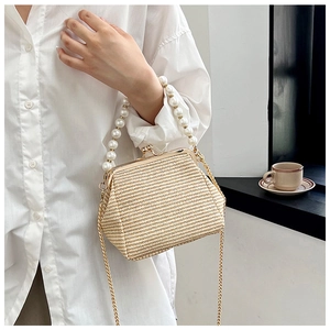 Détail d'un sac en paille tressée avec poignée en perles et fine chaîne dorée