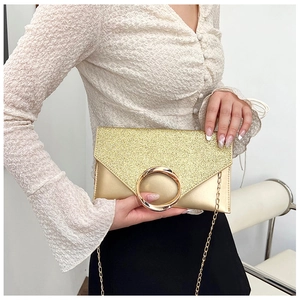 Detail view of a gold glitter envelope clutch bag with metal ring and chain strap