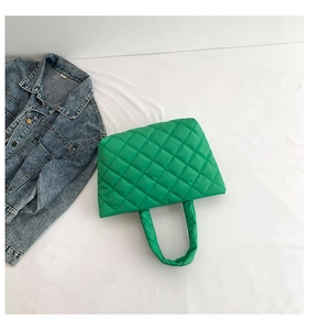 Quilted green puffer tote bag detail with diamond stitching on blue denim jacket