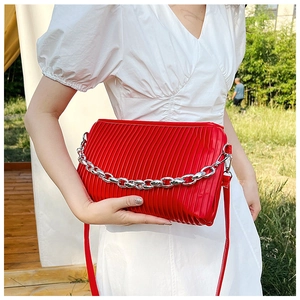 Detail of red pleated shoulder bag with chunky silver chain in natural outdoor light
