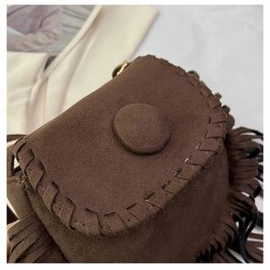 Detailed close-up of dark brown suede saddle bag featuring long tassels and stitched edges