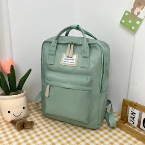 Detail of mint green campus backpack with cream leather zipper pulls and woven logo tag