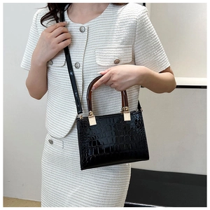 Detail of glossy black faux leather tote with crocodile pattern and amber resin handle