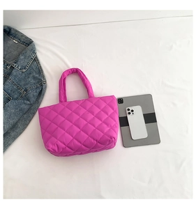 Detailed top view of a large pink puffy tote bag showing capacity with a tablet and phone