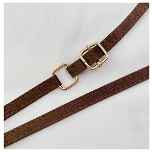 Detail of dark brown suede shoulder strap with polished gold-tone metal buckle and stitching