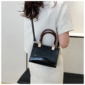 Detail of black crocodile texture bag with resin handle shown on a shoulder
