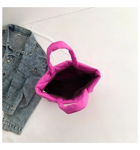 Flat lay macro view of bright pink quilted puffer tote bag with spacious interior zipper