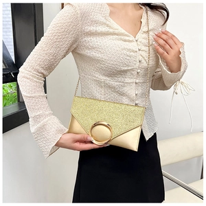 Close-up of gold envelope clutch bag featuring glitter fabric and metallic round buckle