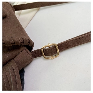 Detail of dark brown suede saddle bag showing adjustable strap with gold metal buckle