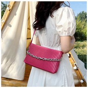 Detail of fuchsia pleated shoulder bag with bold silver chain and modern metallic finish