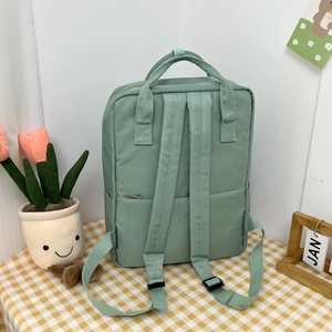 Detail view of the mint green canvas backpack featuring a back anti-theft zipper pocket