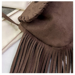 Detail of suede crossbody bag featuring retro whipstitch edges and long fringe tassels