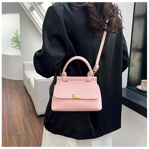 Detail shot of the pink lychee pattern crossbody bag with golden hardware on a model