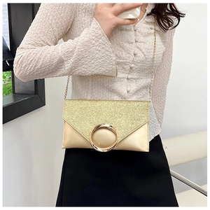 Macro view of champagne gold envelope clutch featuring sequins and a large metal ring