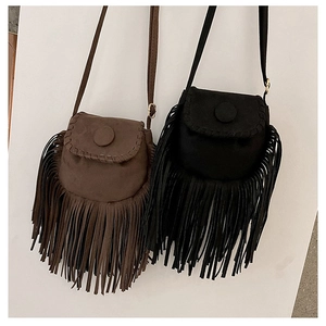 Close-up of brown and black suede saddle bags with long fringe tassels and flap closure