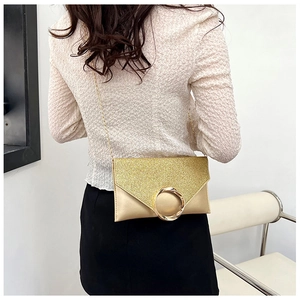 Detail view of a gold envelope clutch with sequins and metal ring buckle worn by model