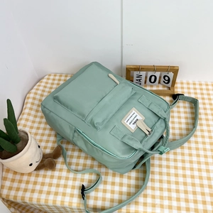 Detail view of mint green nylon backpack showing front pocket and side storage pockets