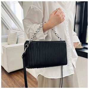Detail of black pleated rectangular crossbody bag with bold silver chain handle and strap