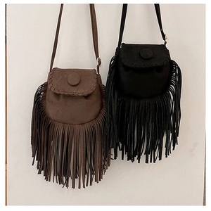 Detail of suede-like crossbody bags with long tassels and hand-woven stitching on flap