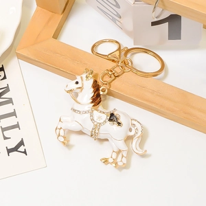 Dettaglio portachiavi a forma di cavallo in smalto bianco con placcatura in oro e strass