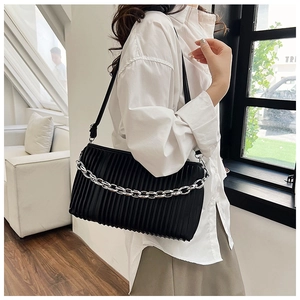 Detail of black pleated shoulder bag with chunky silver chain and matte finish on model