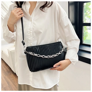 Detail of black pleated shoulder bag featuring a bold silver chain and smooth PU leather texture