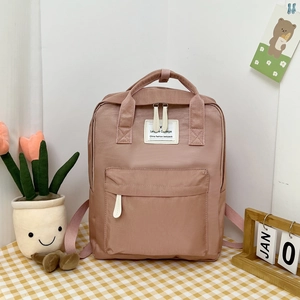 Detail of a sweet pink college-style backpack on a checkered desk with decor