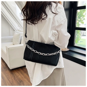 Detail shot of a black pleated crossbody bag with a thick silver metal chain and shoulder strap