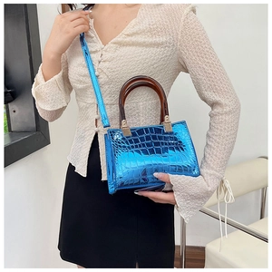 Fashionable electric blue crocodile pattern handbag with glossy finish and tortoiseshell handles