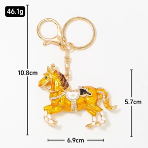 Portachiavi a forma di cavallo dorato con smalto giallo e strass su sfondo bianco