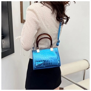 Detail of blue crocodile pattern tote bag with amber resin handles and silver hardware