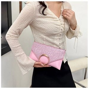 Pink glitter envelope clutch with golden round buckle and chain strap on a model