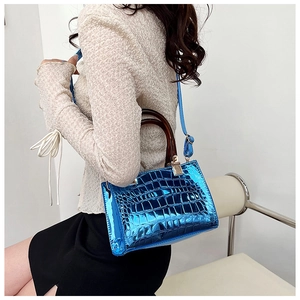 Model view of blue croc-embossed tote bag with tortoiseshell handle and gold hardware