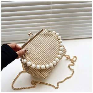 Détail du sac en paille tressée avec anse en perles et bandoulière dorée