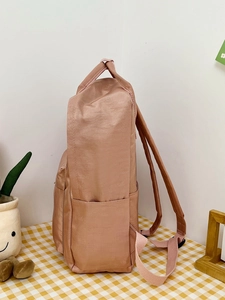 Side view of a light pink high-capacity backpack with side pocket and adjustable straps