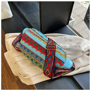Detail of colorful geometric ethnic embroidery and gold zipper on blue crossbody bag