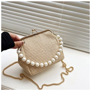 Détail d'un sac shell en paille tressée beige avec poignée en perles et chaîne dorée