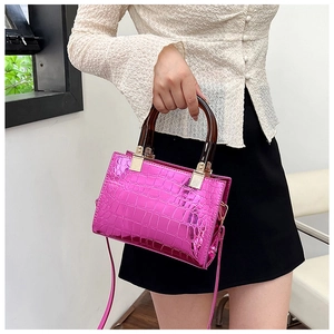 Detail view of pink crocodile textured tote with amber handles and gold hardware