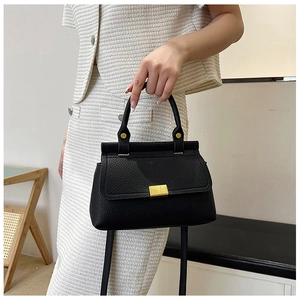Close-up of black lychee grain leather handbag with gold chain handle and hardware detail