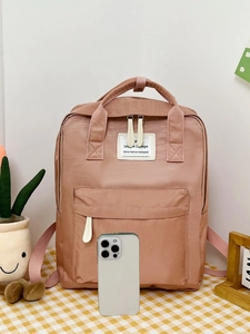 Pink student backpack with double handles and front pocket shown next to a smartphone