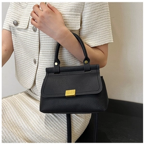 Close-up of black lychee leather handbag with elegant gold metal buckle and texture