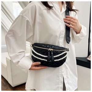 Détail du sac de poitrine noir matelassé avec chaînes de perles et zip doré sur modèle