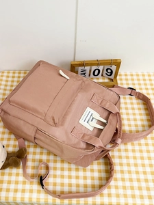 Pink nylon backpack detail with front zipper pocket and white label on checkered cloth